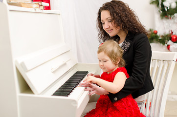 mother and daughter playing on white piano