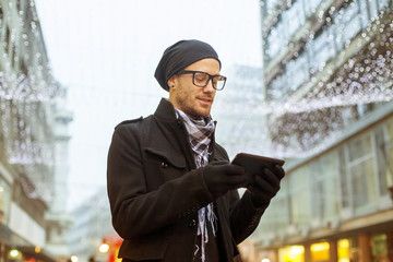 Urban man holdin tablet computer on street