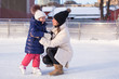 © travnikovstudio - Smiling young mother and her cute little daughter ice skating