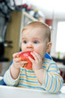 Baby with an apple at home; vertical