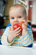 Baby with an apple at home;vertical