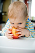 Baby with an apple at home;vertical