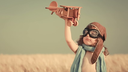 Wall Mural - Happy kid playing with toy airplane against summer sky