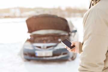 closeup of man with broken car and smartphone