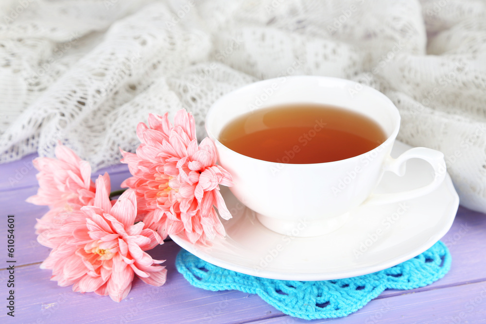 Pink chrysanthemums and cup of tea on wooden table