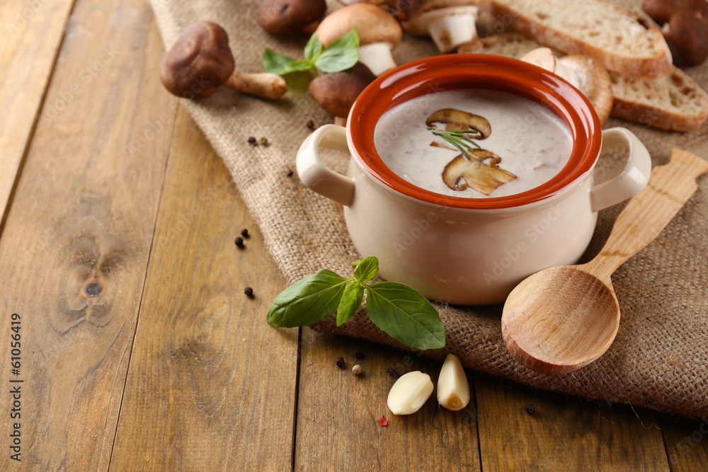 Mushroom soup in pot, on wooden background