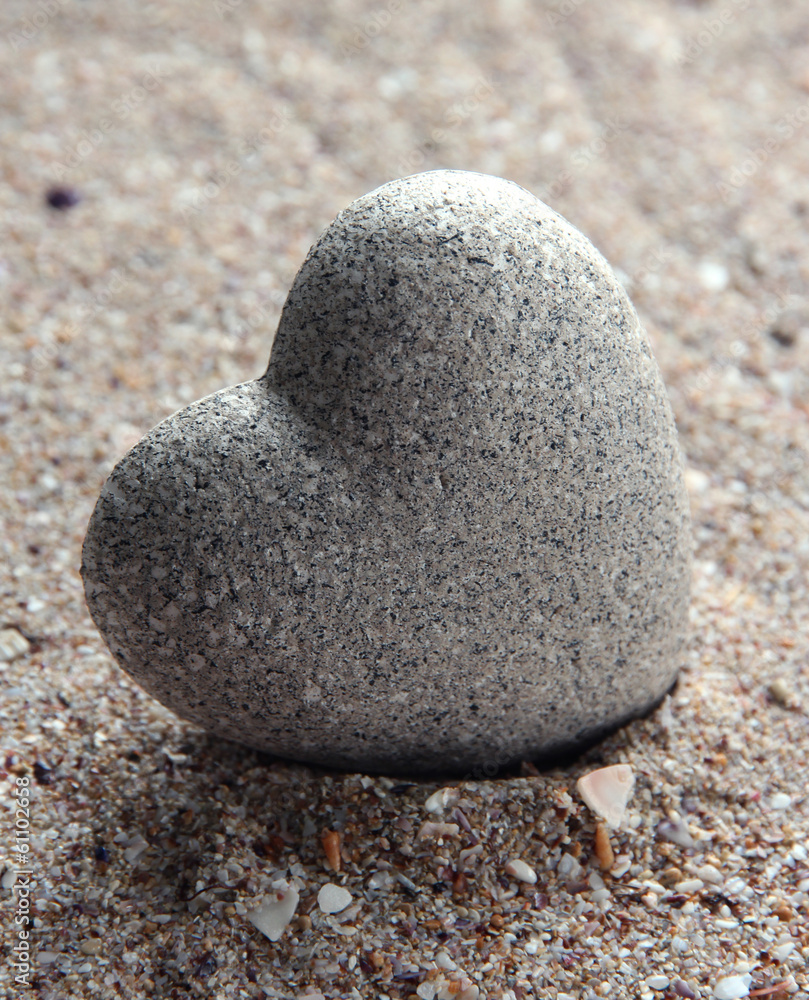Grey stone in shape of heart, on sand background