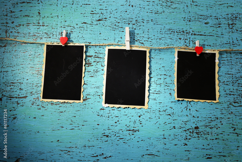 Blank old photos on rope on color wooden background