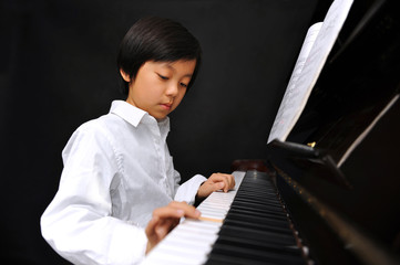 Young boy playing piano (isolated on black background)