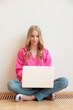 © sepy - Close-up of young woman sitting on floor and using laptop
