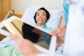 Wall Mural - Patient With Doctor Using Digital Tablet In Foreground