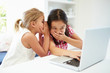 © Monkey Business - Two Young Girls Using Laptop At Home And Whispering