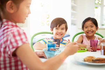 Three Asian Children Having Breakfast Together In Kitchen