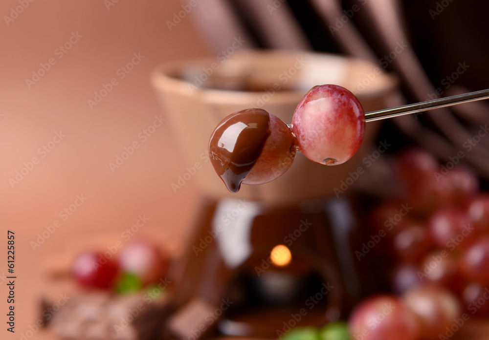 Chocolate fondue with fruits, on  brown background