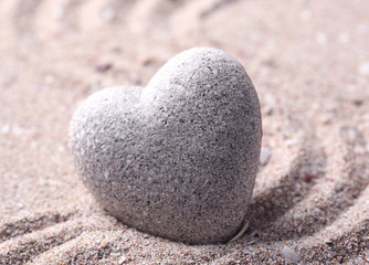 Wall Mural - Grey zen stone in shape of heart, on sand background