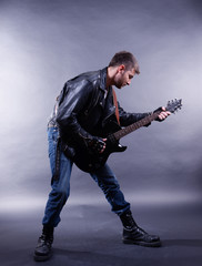 Wall Mural - Young musician playing  guitar on gray background