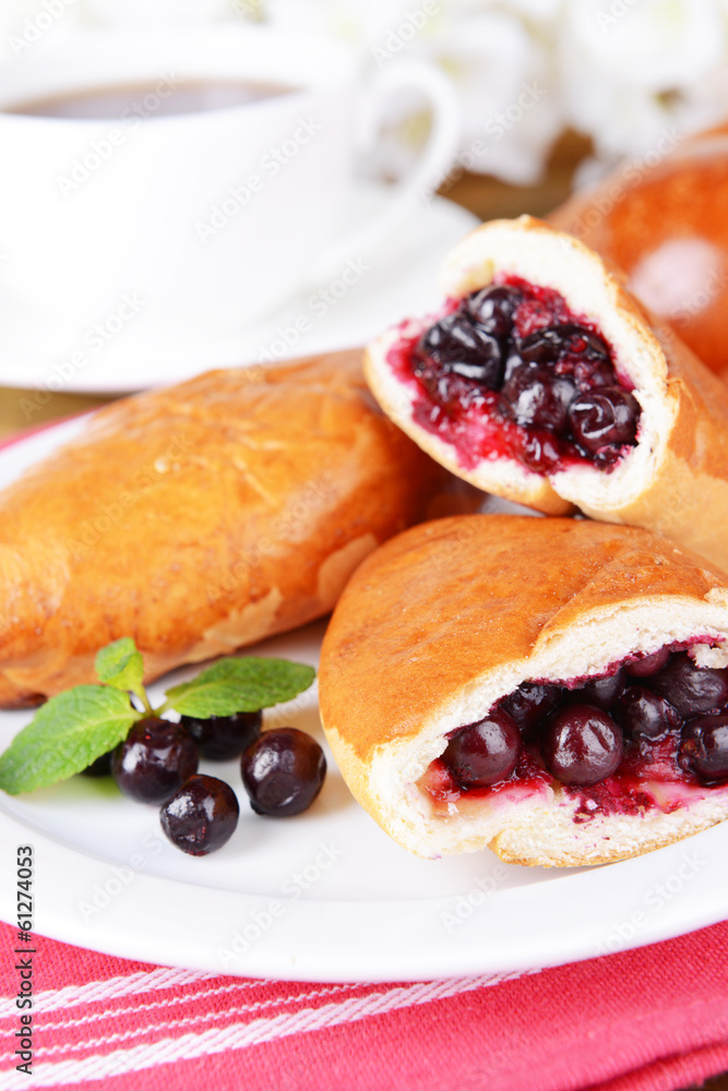 Fresh baked pasties with currant on plate on table close-up