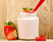 Strawberry yogurt on wooden background with a red spoon