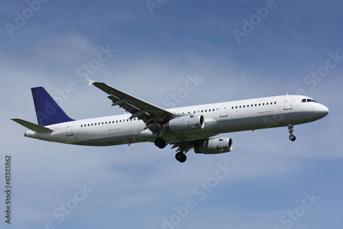 Naklejka ścienna White plane with blue tail landing in sunny day