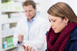 © contrastwerkstatt - kundin in der apotheke schaut auf medikament