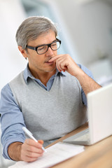 Senior businessman in office working on laptop