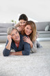 © goodluz - Middle-aged couple with little girl laying on carpet