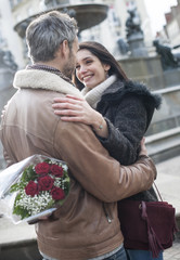 romantic guy holding red roses behind his back for his girlfrien