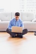 © WavebreakMediaMicro - Happy businessman sitting on floor using his laptop
