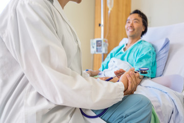 Doctor Sitting With Patient On Hospital Bed