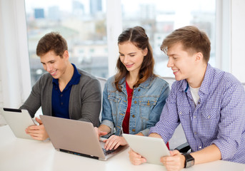 Wall Mural - three smiling students with laptop and tablet pc