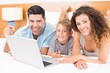 © WavebreakMediaMicro - Smiling young family using laptop to shop online together on bed