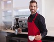 © WavebreakmediaMicro - Handsome young barista holding jug and cup of coffee