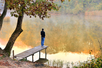 autumn landscape reflected in the water facing the young