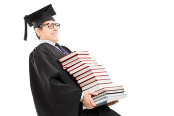 Wall Mural - Young man in graduation gown carrying bunch of books