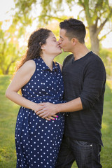 Wall Mural - Hispanic Man Kisses His Pregnant Wife Outdoors At the Park