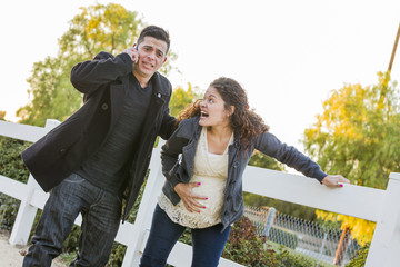 Wall Mural - Pregnant Woman In Pain While Husband Uses Cell Phone Outside