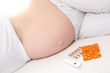Schwangere Frau mit Medikamenten im Bett