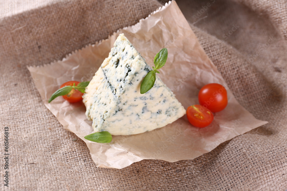 Tasty blue cheese with tomatoes and basil, on burlap background