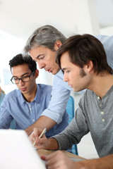 Students in class with teacher helping with work