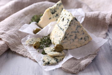 Wall Mural - Tasty blue cheese with thyme and olives on paper