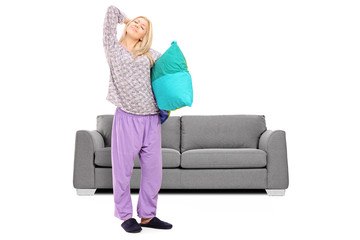 Sticker - Young woman in pajamas stretching in front of a sofa