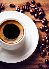 Wall Mural - Coffee cup with white saucer and roasted coffee beans  on wooden