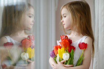 Wall Mural - Adorable little girl with tulips by the window