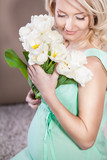 Fototapeta Tulipany - Pregnant woman holding in hands bouquet of flowers