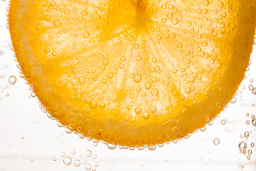 Wall Mural - close-up of lemon slice in clear water with bubbles