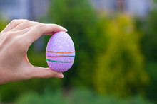 Bright Purple Easter Egg In Hand On Background Of Blue Sky