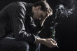 © bramgino - Depressed smoking man sitting on chair on black background
