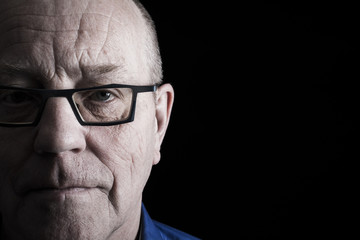 Closeup portrait of older man on black background.