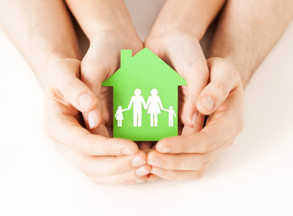 hands holding green house with family