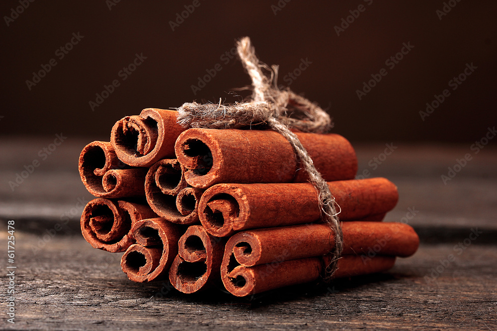 Cinnamon sticks on wooden table on brown background